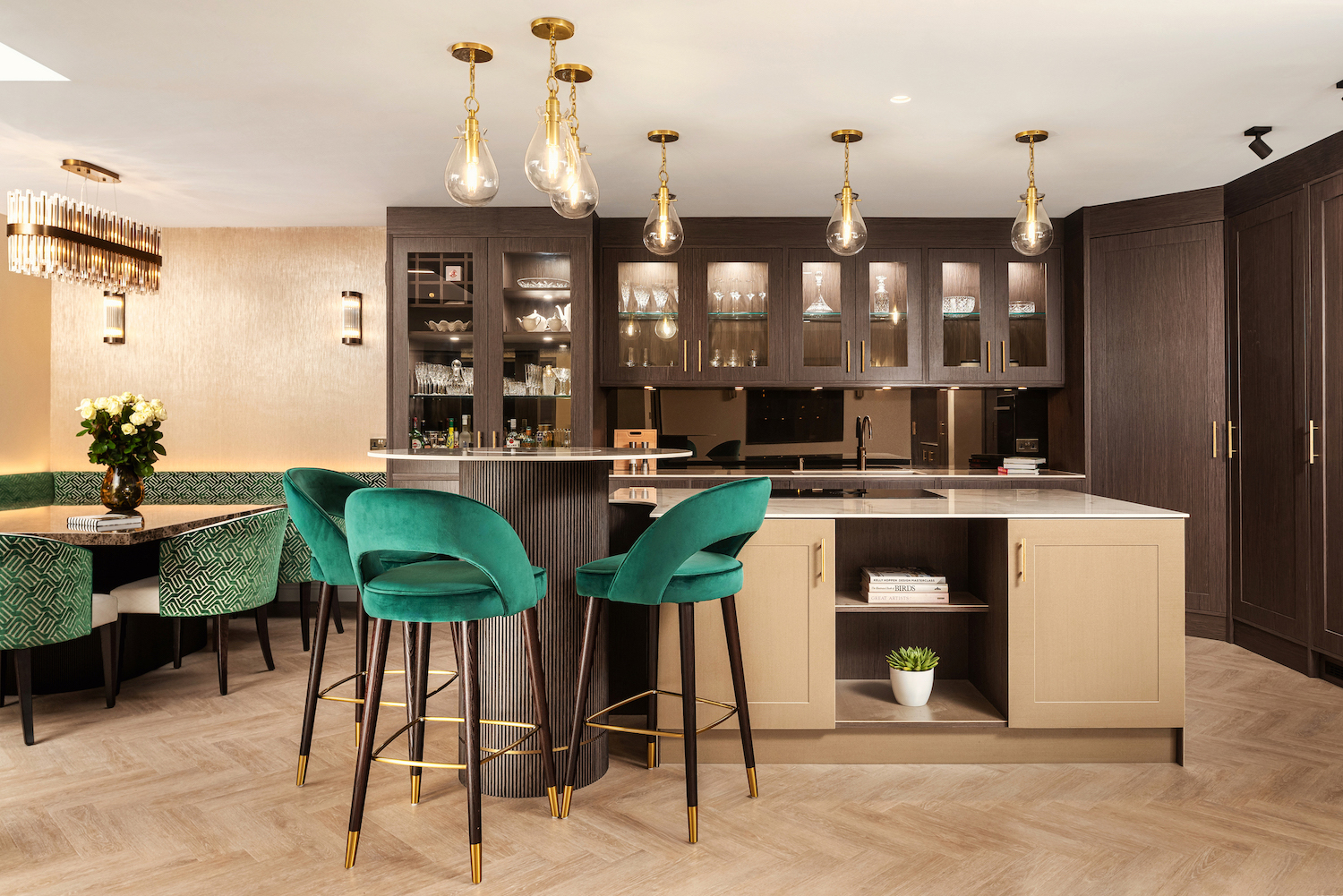 Luxury kitchen with dark walnut cabinetry, brass pendant lights, emerald velvet bar stools, and layered lighting design by Katie Malik Design Studio