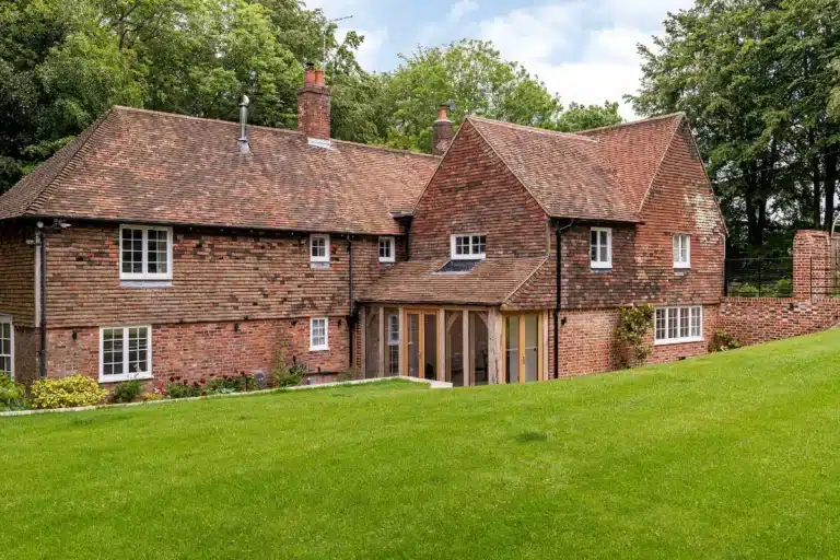 Grade II listed brick house with sympathetic modern extension featuring conservatory, demonstrating successful blend of heritage architecture and contemporary design