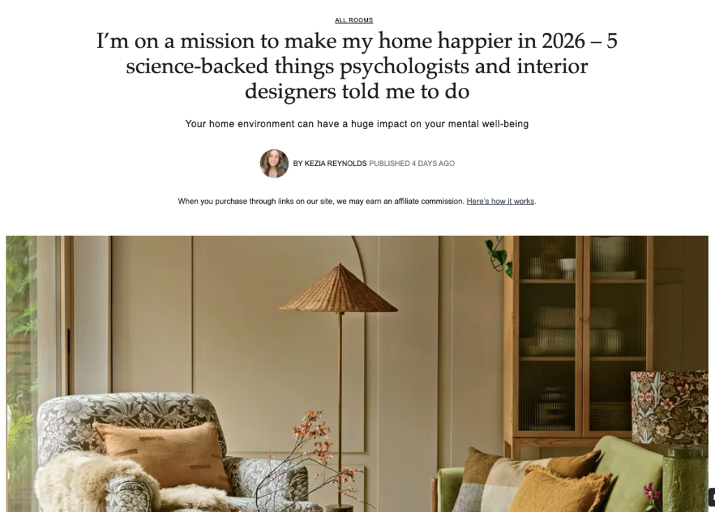 Warm neutral living room with natural textures featuring wicker floor lamp, patterned armchair, and sage green cabinetry demonstrating Katie Malik's interior design principles for happier homes